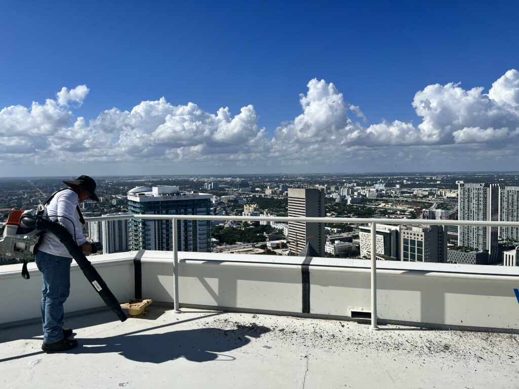 Clarity Roofing technician working on a high-rise rooftop overlooking the South Florida skyline